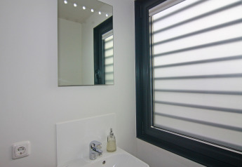 Modernes Badezimmer mit Spiegel, Waschbecken, Seifenspender und großem Fenster in einem Hausboot.