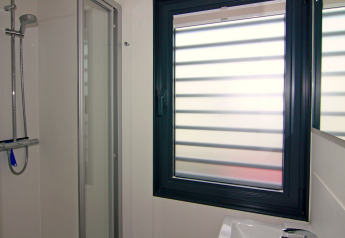 Badezimmer auf einem Hausboot mit moderner Dusche, Fenster mit Jalousien und Waschbecken in Ribnitz-Damgarten.