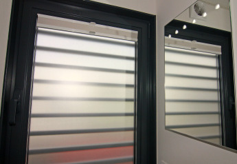 A modern window with blinds and its reflection in a wall mirror, photographed on a houseboat in Germany.