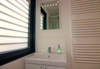 Modern bathroom with mirror, sink, soap dispenser, and large window on the Floating Houses Blue Active houseboat in Germany.