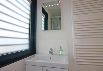 Modernes Badezimmer mit Spiegel, Waschbecken, Seifenspender und großem Fenster im Hausboot Floating Houses Blue Active, Deutschland.