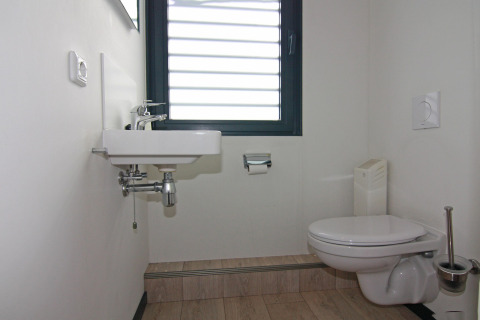 Modernes Badezimmer auf einem Hausboot mit Wandtoilette, Waschbecken und Fenster in Ribnitz-Damgarten.
