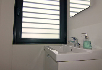 Baño moderno en una casa flotante con lavabo rectangular, grifo cromado y dispensador de jabón junto a la ventana.