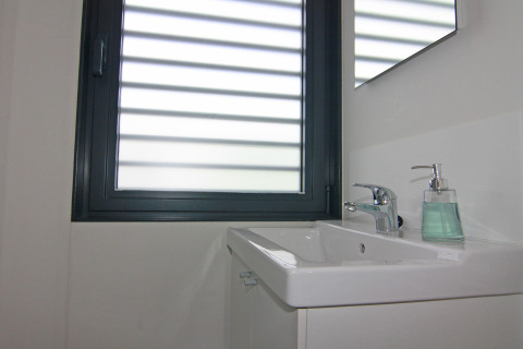 Modernes Badezimmer auf einem Hausboot mit rechteckigem Waschbecken, Wasserhahn und Seifenspender.