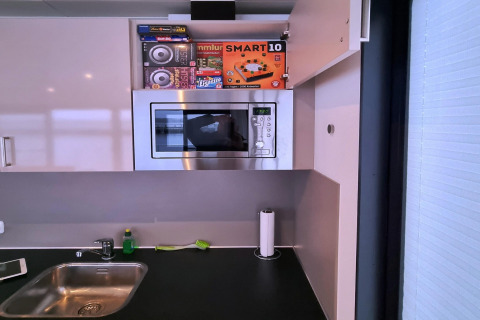 Cuisine moderne sur une péniche avec évier, micro-ondes, porte-serviettes et placard ouvert en Allemagne.