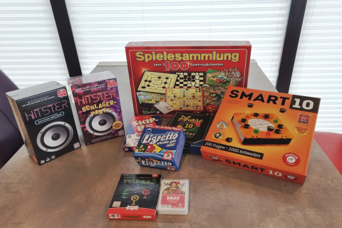 Brætspil som Smart 10, Hitster og Spielesammlung på et bord i et lyst rum på en husbåd i Tyskland.