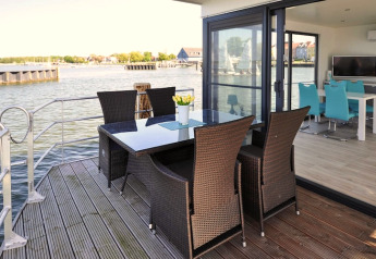 Terrasse des Hausboots 'Leni' mit Esstisch, Stühlen und Wasserblick in Deutschland.