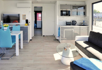Modernes Interieur eines Hausboots mit blauen Stühlen, grauem Sofa und Küche in Ribnitz-Damgarten.