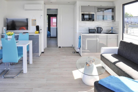 Modernes Interieur eines Hausboots mit blauen Stühlen, grauem Sofa und Küche in Ribnitz-Damgarten.