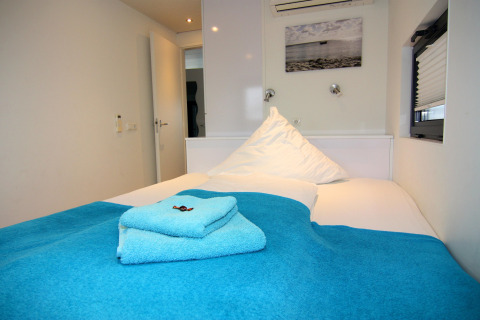 Dormitorio en la casa flotante 'Floating House Leni', Ribnitz-Damgarten, Alemania con toallas azules en la cama.
