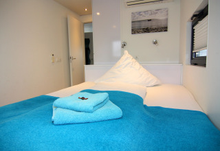 Schlafzimmer im Hausboot 'Floating House Leni' in Ribnitz-Damgarten, Deutschland mit blauen Handtüchern.