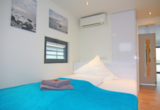 Modernes Schlafzimmer auf dem Hausboot in Ribnitz-Damgarten, Deutschland, mit blauem Bettbezug.