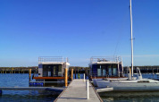 Péniche 'Floating House Luisa' au port de Ribnitz-Damgarten, Allemagne, sous un ciel bleu dégagé.