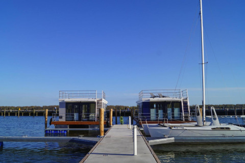 Hausboot 'Floating House Luisa' im Hafen von Ribnitz-Damgarten, Deutschland, bei klarem Himmel.