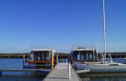 Casa flotante 'Luisa' en el puerto de Ribnitz-Damgarten, Alemania, bajo un cielo azul despejado.