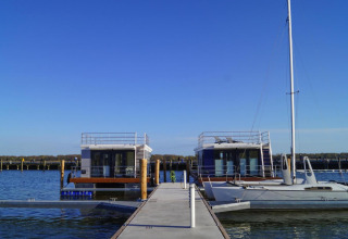 Péniche 'Floating House Luisa' au port de Ribnitz-Damgarten, Allemagne, sous un ciel bleu dégagé.