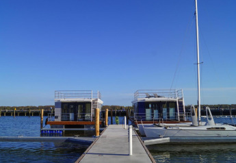 Péniche 'Floating House Luisa' au port de Ribnitz-Damgarten, Allemagne, sous un ciel bleu dégagé.
