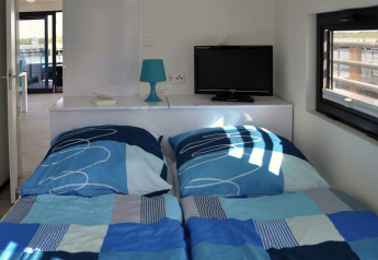 Schlafzimmer auf Hausboot Floating House Luisa in Deutschland mit zwei Betten, Fernseher und Fenster.