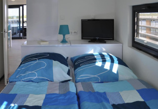 Dormitorio en la casa flotante Luisa en Alemania con dos camas, televisor, lámpara y ventana vista.