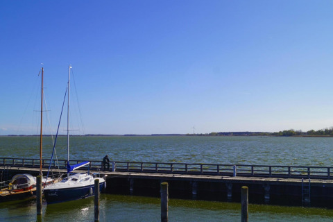 Vista desde la casa flotante 'Luisa' en Ribnitz-Damgarten, Alemania, con veleros y muelle junto al lago.
