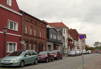 Ruhige Straße in Ribnitz-Damgarten, Deutschland, mit historischen Gebäuden und parkenden Autos bei bedecktem Himmel.