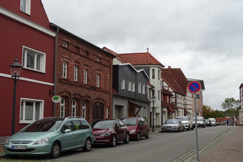 Calle tranquila en Ribnitz-Damgarten, Alemania, con casas coloridas y coches estacionados en un día nublado.