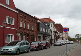 Calle tranquila en Ribnitz-Damgarten, Alemania, con casas coloridas y coches estacionados en un día nublado.