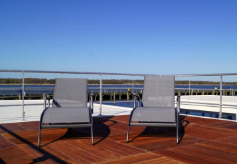 Zwei Sonnenliegen auf dem Deck des Hausboots „Luisa“ mit Blick aufs Wasser in Ribnitz-Damgarten, Deutschland.