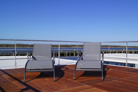 Zwei Sonnenliegen auf dem Deck des Hausboots „Luisa“ mit Blick aufs Wasser in Ribnitz-Damgarten, Deutschland.