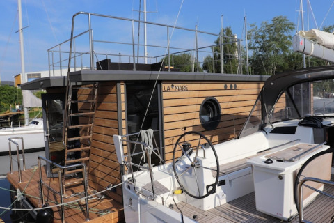 Moderne woonboot genaamd Leni aangemeerd in Duitsland met houten gevel en rond patrijspoort raam.