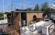 Moderne woonboot genaamd Leni aangemeerd in Duitsland met houten gevel en rond patrijspoort raam.