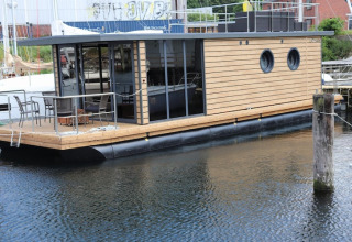 Casa flotante moderna Houseboat «Leni» con ventanas redondas, atracada al muelle en Alemania.