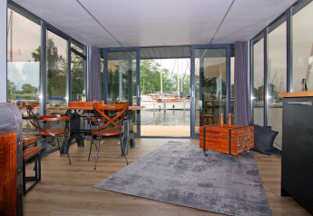 Indvendig udsigt fra Houseboat «Leni» i Tyskland med store vinduer, borde og udsigt til havnen.
