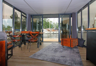 Indvendig udsigt fra Houseboat «Leni» i Tyskland med store vinduer, borde og udsigt til havnen.
