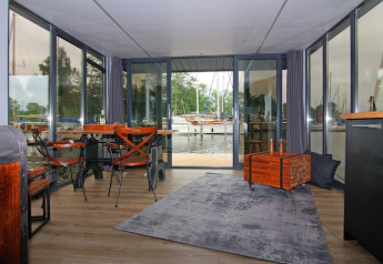 Intérieur de la Houseboat «Leni» en Allemagne avec de grandes fenêtres, coin repas et vue sur le port.