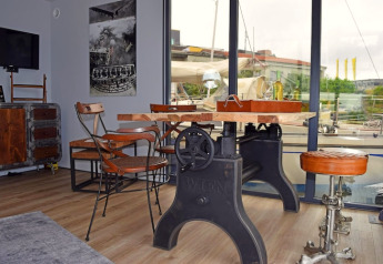 Industrielt inspireret stue på husbåden Leni i Tyskland med store vinduer og unikke møbler.