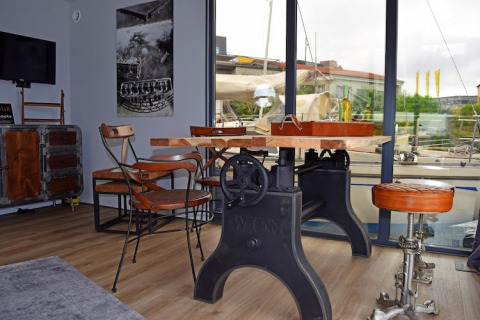 Sala de estar de estilo industrial en la casa flotante Leni en Alemania, con grandes ventanales y muebles de metal.
