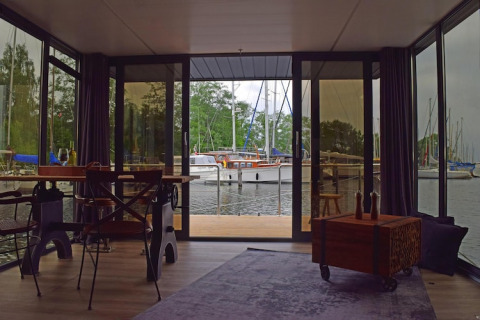 View from inside the Houseboat ‘Leni’ in Germany with large windows overlooking the marina and boats.