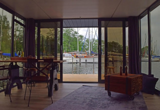 Udsigt fra stuen på husbåden 'Leni' i Tyskland med panorama vinduer over havnen og sejlbåde.