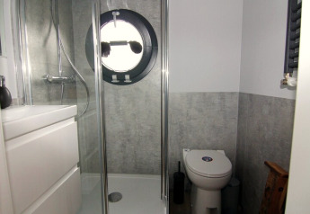 Moderne badkamer op woonboot met rond raam, douche, toilet en wit meubel, Houseboat «Leni», Duitsland.