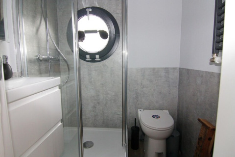Moderne badkamer op woonboot met rond raam, douche, toilet en wit meubel, Houseboat «Leni», Duitsland.