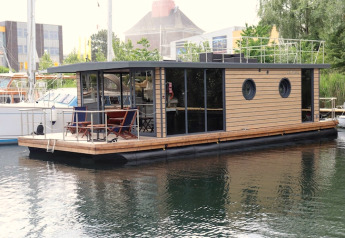 Moderne woonboot genaamd Houseboat «Lina» in Duitsland, aangemeerd in een rustige haven.