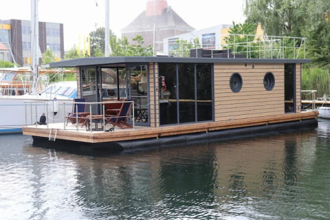 Modern houseboat named Houseboat «Lina» in Germany, docked at a peaceful marina on a summer day.