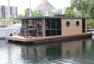 Modern houseboat named Houseboat «Lina» in Germany, docked at a peaceful marina on a summer day.