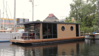 Het moderne woonboot Houseboat Lina ligt aangemeerd aan een steiger, omgeven door andere boten.