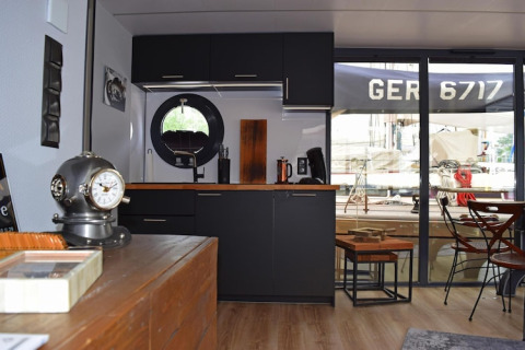 Modern kitchen on houseboat Lina in Germany with black cabinets, round window, and nautical decor.