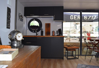 Modern kitchen on houseboat Lina in Germany with black cabinets, round window, and nautical decor.