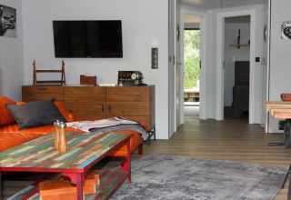 Living area on houseboat 'Lina' in Germany with orange sofa, wooden furniture, and view into bedrooms.