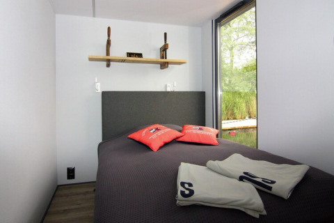 Cozy bedroom on Houseboat 'Lina' in Germany with large window, nature view, and modern decor.