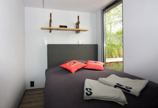 Cozy bedroom on Houseboat 'Lina' in Germany with large window, nature view, and modern decor.